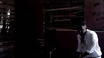 a man standing in a dark room next to a wall