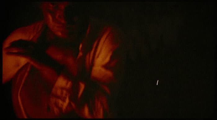 a man standing in the dark with his arms crossed