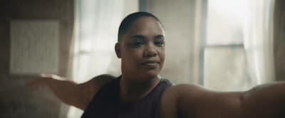 a woman in a tank top standing in front of a window