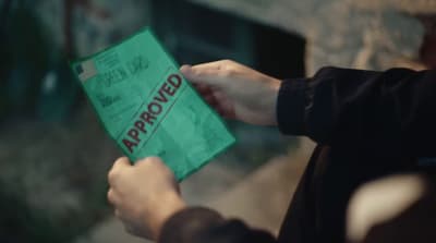 a person holding a green bag with the word approved on it