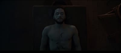 a shirtless man standing in a dark room