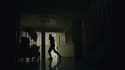 a woman walking down a hallway in the dark