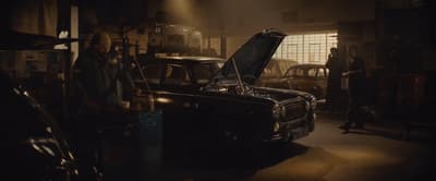 a man standing next to a car in a garage