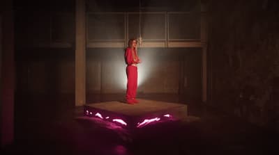 a woman in a red jumpsuit standing on a platform
