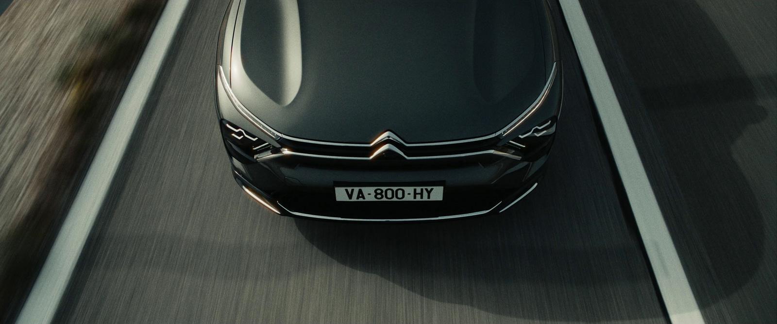a black car driving down a highway next to a forest
