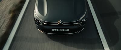 a black car driving down a highway next to a forest