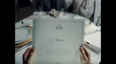 a person holding up a menu at a table