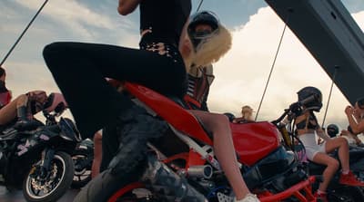 a woman sitting on a red motorcycle in front of a group of people