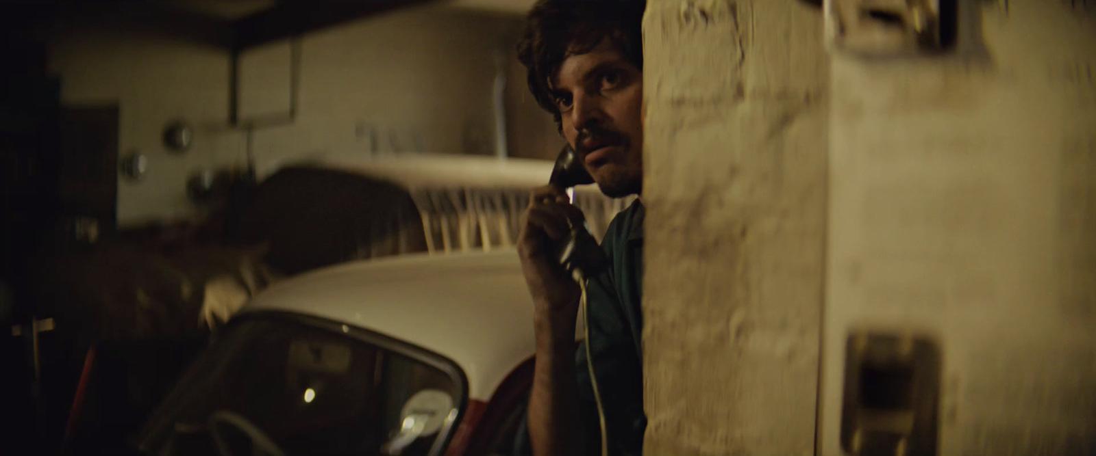 a man talking on a cell phone next to a car
