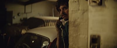 a man talking on a cell phone next to a car