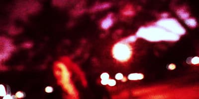 a blurry image of a woman walking down a street at night