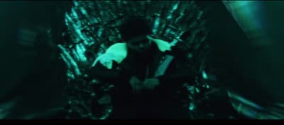 a man sitting on a iron throne in a dark room