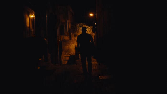 a man standing in a dark alley at night