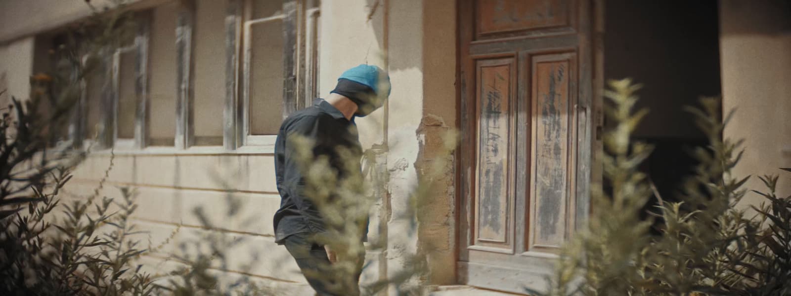 a man standing outside of a building with a blue hat on