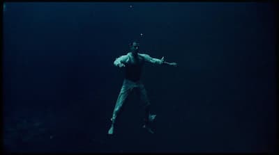 a man standing in the water holding a tennis racquet