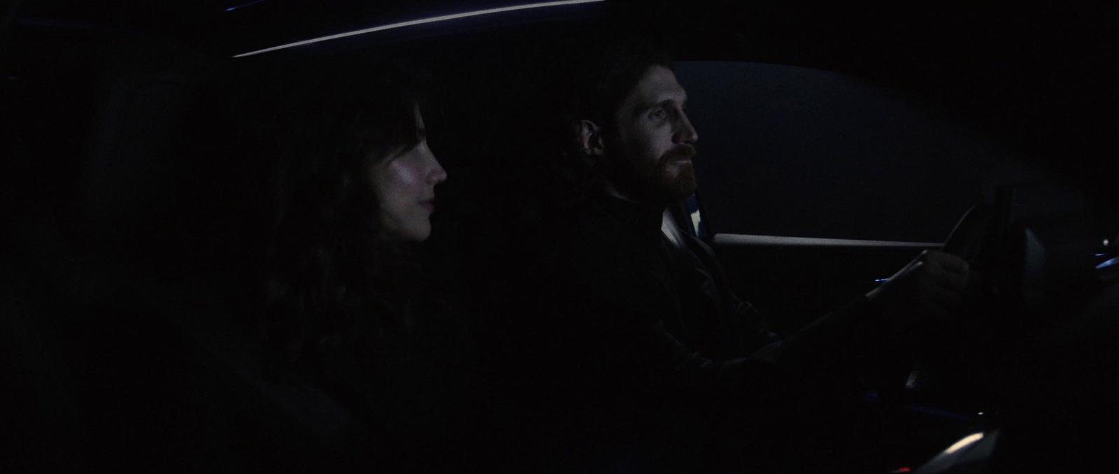 a man and a woman sitting in a car at night