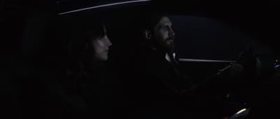 a man and a woman sitting in a car at night