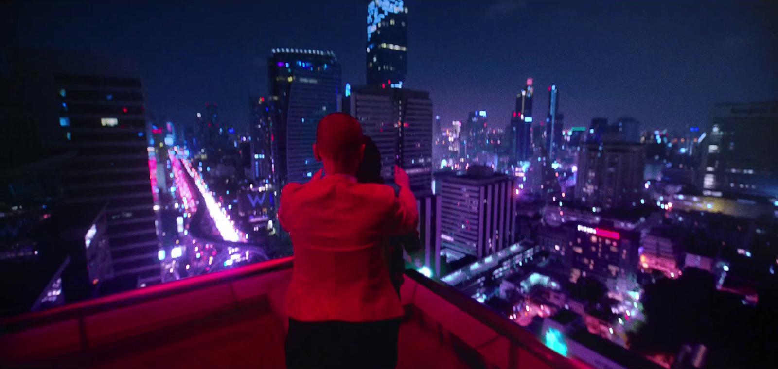 a woman in a red jacket looking out over a city at night