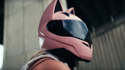 a woman wearing a pink helmet with a black cat on it