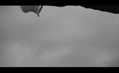 a black and white photo of a kite flying in the sky