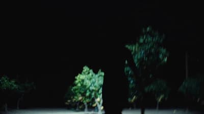 a person standing in the dark with a skateboard