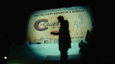 a silhouette of a man standing in front of a sign