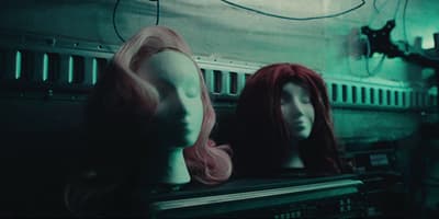 two mannequins with pink hair sitting on top of a shelf