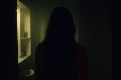 a woman standing in front of a bathroom mirror
