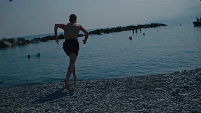 a man walking on a beach next to a body of water