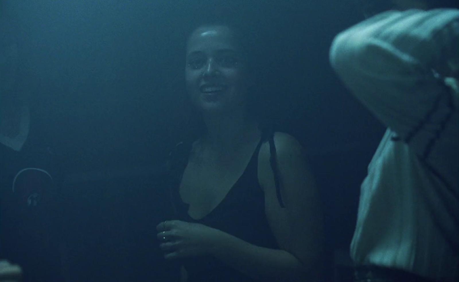 a woman standing in a dark room next to a man