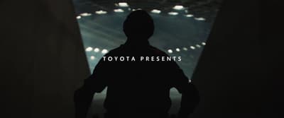 a person standing in a dark room with the words toyota presents