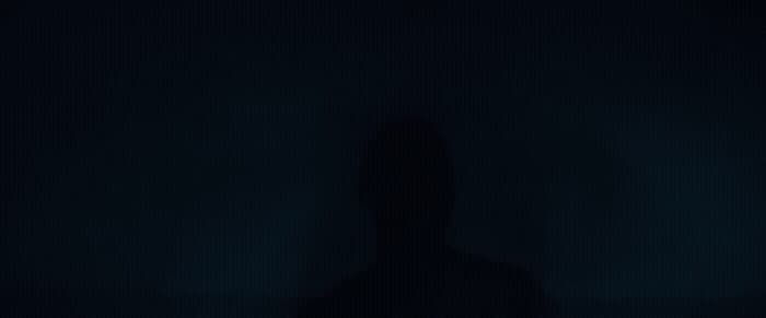 a person standing in the dark with their shadow on the wall
