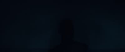 a person standing in the dark with their shadow on the wall