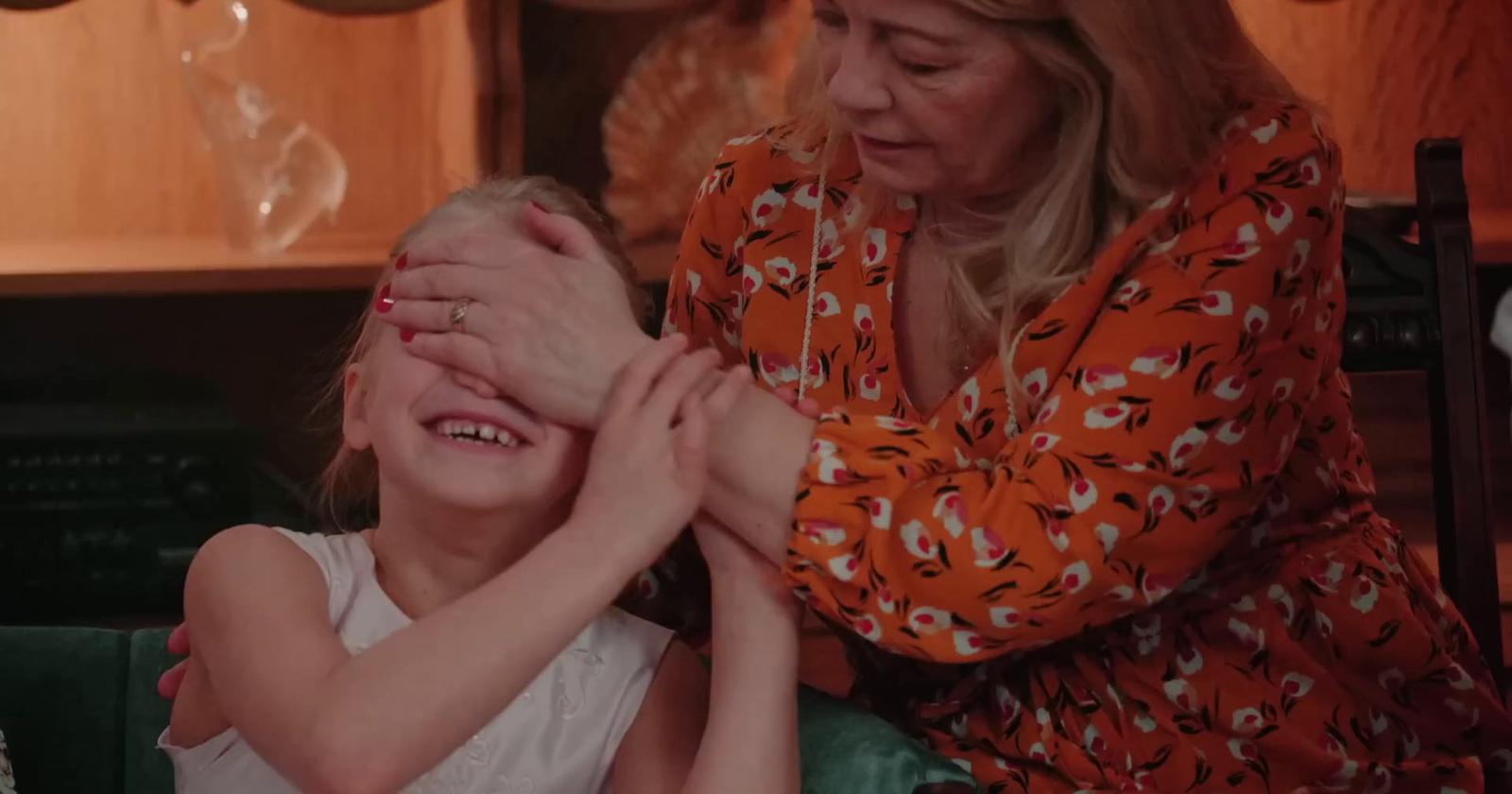 a woman helping a little girl put her hands on her face