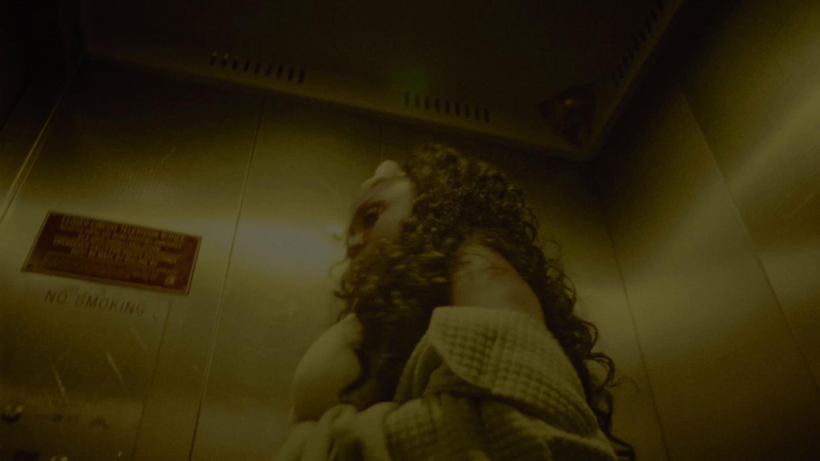 a man with long hair standing in a bathroom