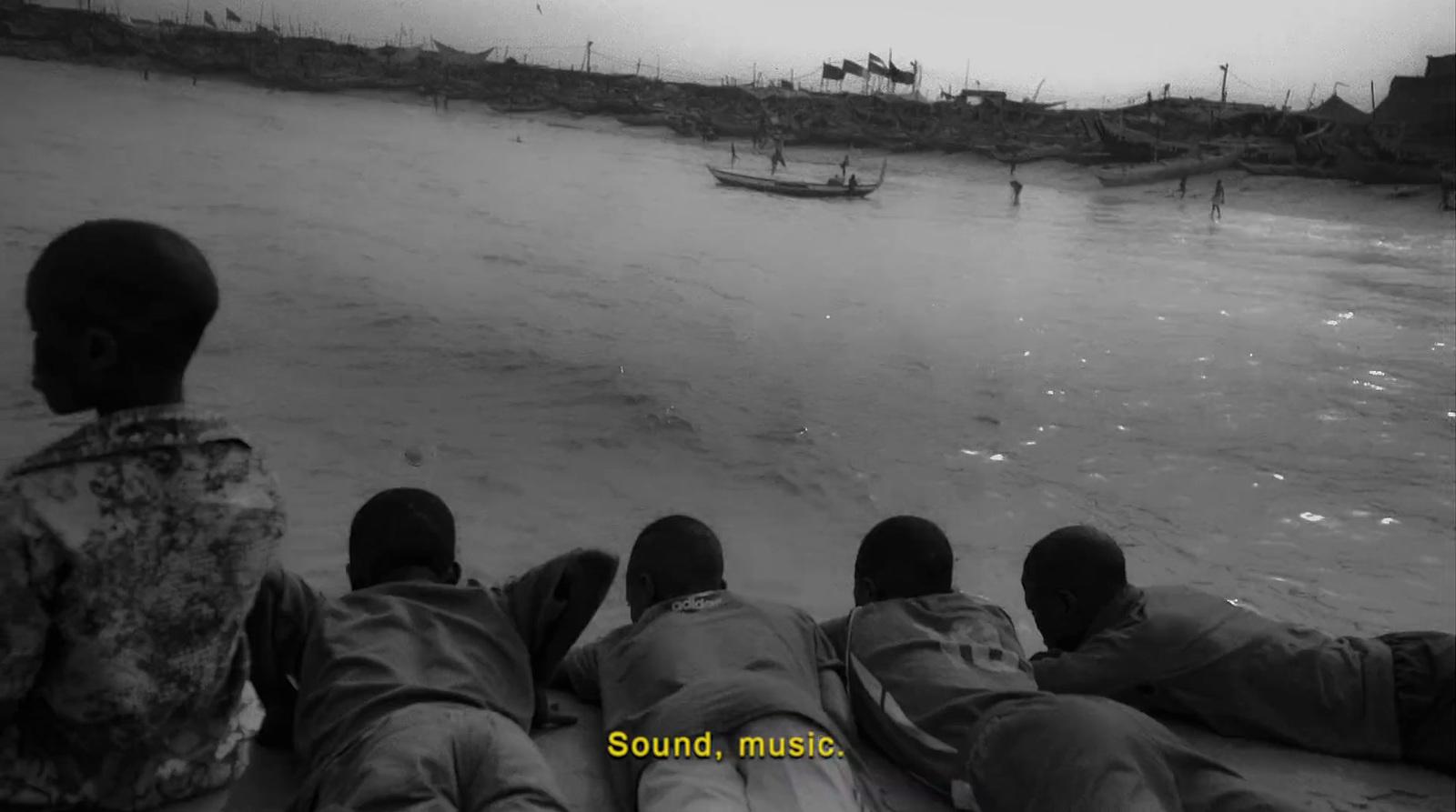a group of people sitting on top of a beach next to a body of water
