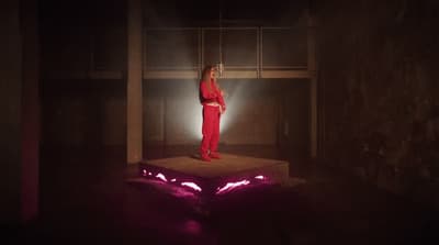 a woman in a red suit standing on a platform