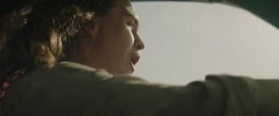 a man driving a car with his hand on the steering wheel