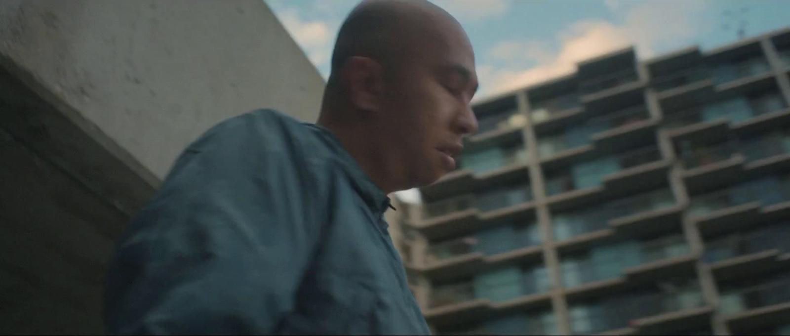 a bald man standing in front of a tall building