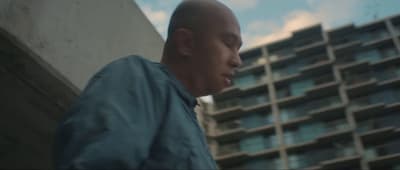 a bald man standing in front of a tall building