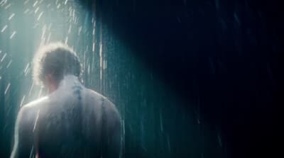 a man standing in the rain with his back to the camera