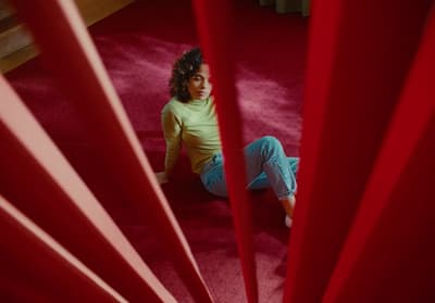 a woman sitting on the floor in front of a red curtain