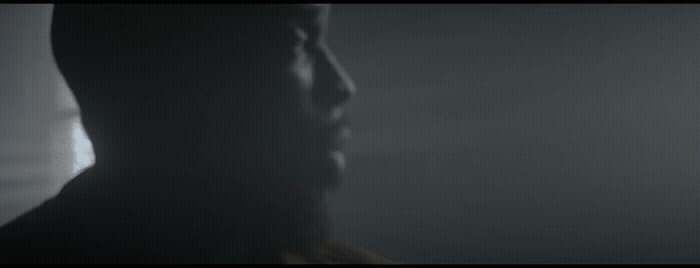 a man standing in a dark room with his head turned to the side