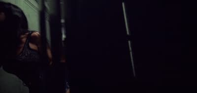 a woman standing in a dark room next to a wall
