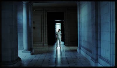 a person standing in a hallway with columns