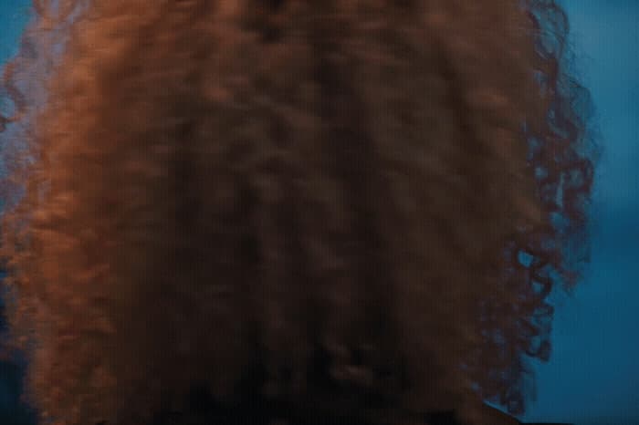 the back of a woman's head with long, curly hair