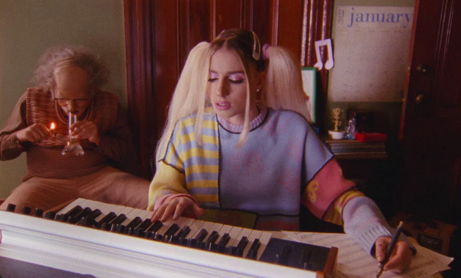 a woman sitting at a piano with a candle in her hand