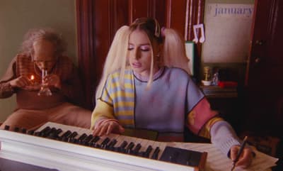 a woman sitting at a piano with a candle in her hand