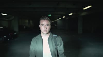 a man standing in a dark parking garage