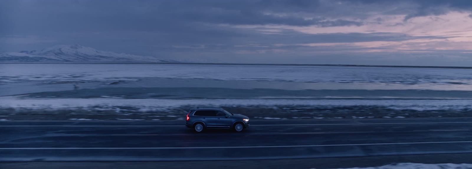 a car driving down a road next to a large body of water
